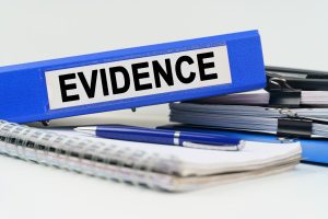 Evidence folders, notebooks and pens on a desk. 
