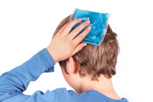 A young person holds an icepack to their head. 