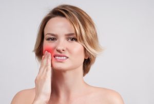 A woman holding her jaw in pain.