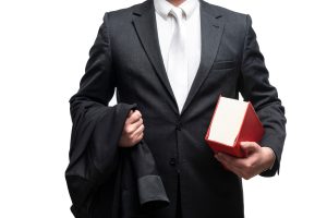 A broken jaw injury solicitor in a suit carrying a red legal book in one hand and their blazer in the other hand.