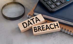 WOODEN BLOCKS THAT READ 'DATA BREACH' ON A DESK IN THE WORKPLACE