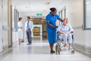Woman in wheelchair being helped by nurse.