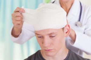 A PERSON HAVING A HEAD INJURY BANDAGED