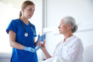 A doctor is giving an elderly patient water and medication 