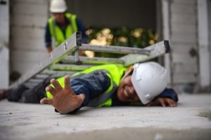 An injured worker lays trapped beneath a collapsed ladder.
