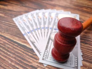Money notes spread out in a fan shape on a table with a gavel on the notes.