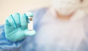 A medical professional holding a small vial 