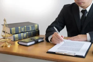 A solicitor making notes on some paperwork about paediatric negligence claims sitting next to gold scales and old fashioned books.