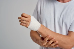 A man holding his forearm wearing a bandage around his wrist.